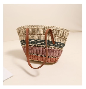 Détail d'un sac cabas en paille à rayures avec des anses en cuir marron et tissage