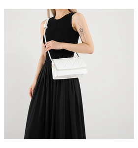 Close-up of white crossbody bag with geometric diamond quilting and PU leather texture
