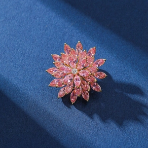 Elegant rotating pink zircon flower brooch with gold plating on a dark textured surface