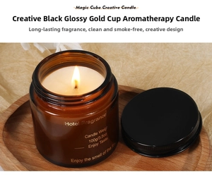 Close-up of a 100g scented candle in amber glass jar lit on a wooden tray with warm glow