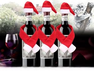 Close-up of mini Santa hats and scarves decorating three wine bottles for Christmas