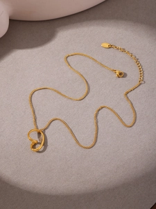 Detailed view of an irregular heart necklace in 18k gold plating on a textured background