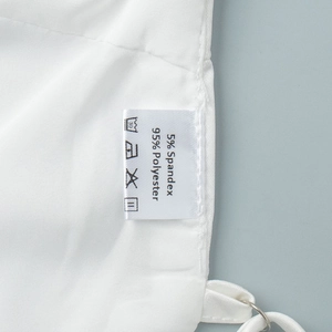 Détail de l'étiquette d'entretien du haut blanc montrant 95% polyester et 5% élasthanne