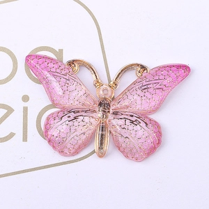 Macro detail of pink translucent resin butterfly pendant with gold metallic edges