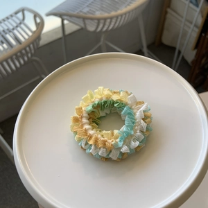 Détail d'un chouchou en dentelle plissée colorée sur un plateau blanc au style épuré