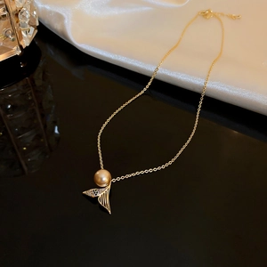 Macro shot of gold fishtail pendant with pearl and sparkling zircon on silk background