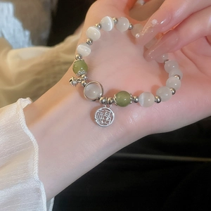 Detailed shot of cat eye bead bracelet with silver Fu character charm on model hand