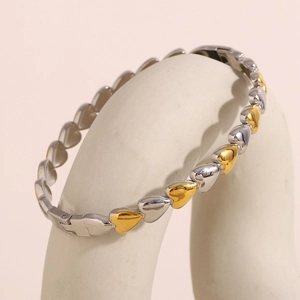 Close-up of two-tone heart link bracelet with 18K gold plating on ceramic display