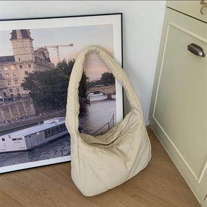 Detail of soft cream quilted nylon hobo bag featuring padded shoulder strap and zipper closure