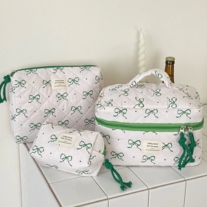 Detailed macro view of quilted makeup bags with green bow patterns in three sizes