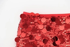 Detailed view of red sequin mini skirt waistband with layered shimmering discs