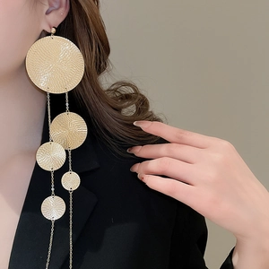 Macro detail of layered golden circular drop earrings showing textured metallic finish