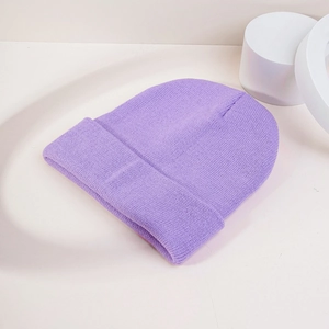 Vue de dessus d'un bonnet en tricot côtelé violet sur un fond blanc minimaliste et épuré