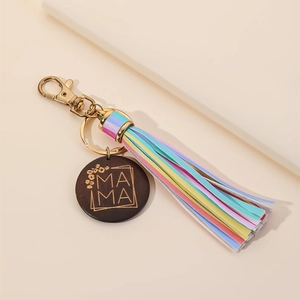 Detail of MAMA wooden keychain with rainbow tassel and golden metal clasp on beige background