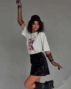 Mannequin à la mode en t-shirt blanc imprimé avec jupe à paillettes noire et bottes en cuir