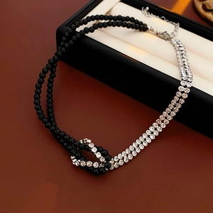 Two-layer beaded necklace with clear crystals and black beads on a luxury jewelry box