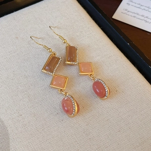 Close-up of vintage gold earrings with pink and brown gemstones and small rhinestones