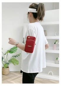 Detail of red nylon phone bag with dual zippers and metal headphone port on the side