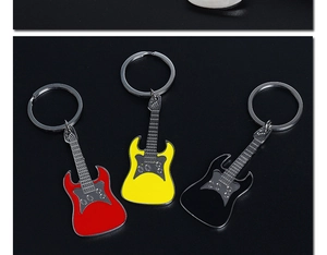 Detailed view of three metal guitar keychains in red, yellow and black on black background
