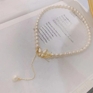 Macro view of freshwater pearl necklace with shell butterfly pendant and golden chain