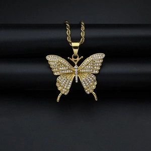 Macro detail of gold butterfly pendant with sparkling rhinestones on twisted rope chain
