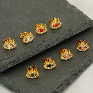 Golden Evil Eye stud earrings set with colorful zircon stones on dark stone background