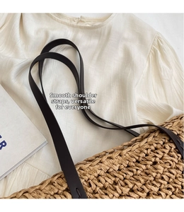 Close-up of natural straw tote bag with black strap and woven texture detail