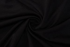 Detailopname van de zwarte gebreide stof met fijne weving en zachte drapering