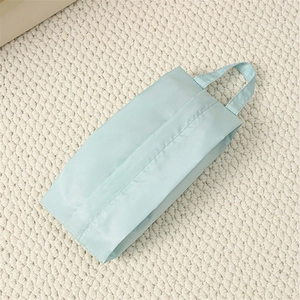 Close-up of light blue portable travel organizer bag on soft white knit texture