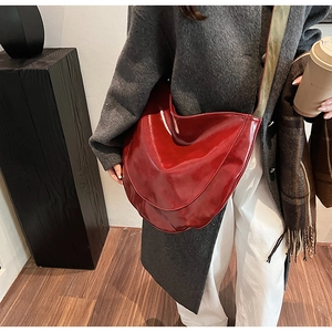 Detailed view of a glossy burgundy PU leather hobo bag styled with a grey winter coat