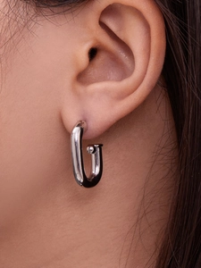 Détail de créoles argentées en forme de U avec finition polie sur l'oreille