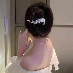 Detailed back view of a silver feather hair clip with pearls and rhinestones on hair