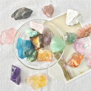 Close-up of assorted natural crystal stones in a glass bowl on white fabric