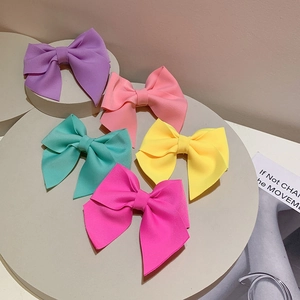Macro shot of 5-piece colorful bow hair clips in neon fabric on a minimalist stone display