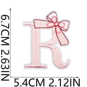 Detail of pink embroidered letter R patch with a delicate bow for DIY clothing decor