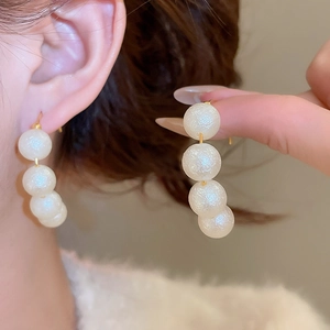 Detail view of French vintage drop earrings with four white pearls and gold hooks