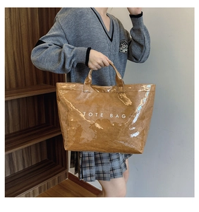Close-up of brown glossy Tyvek tote bag with TOTE BAG print worn by model