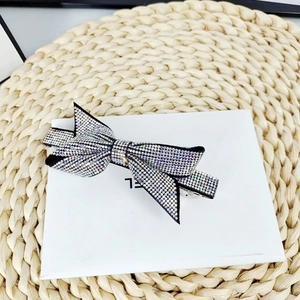 Detail of sparkling crystal rhinestone bow hair clip on a white box and woven mat