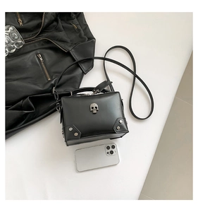 Detailed view of small black crossbody bag with metal skull and silver studs decoration