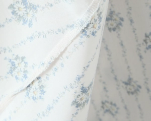 Macro view of blue floral print on white fabric with detailed hem stitching