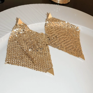 Détail de boucles d'oreilles en maille dorée avec sequins métalliques sur un plateau
