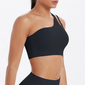 Detail of black one-shoulder sports bra with asymmetric straps and matte elastic fabric