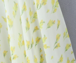 Dettaglio del tessuto in chiffon bianco con stampe floreali gialle e trama leggera