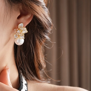 Detail of floral earring with white enamel petals, crystal center and hanging pearl