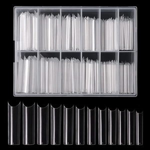 Macro detail of long C-curve clear French nail tips with numbered sizes in 12-grid box