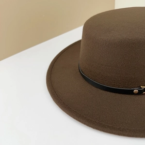 Detail of dark brown wool felt hat showing black leather strap and gold metal buckle