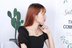 Close-up of a gold geometric cutout pendant necklace worn by a model in a lifestyle setting