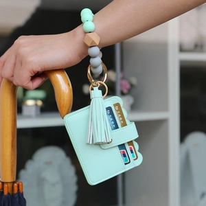 Detail showing mint green leather card holder with silicone bead bracelet and tassel
