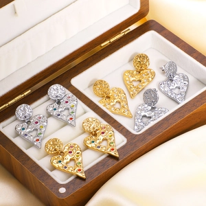 Hammered gold and silver heart earrings with colorful crystals in a wooden jewelry box