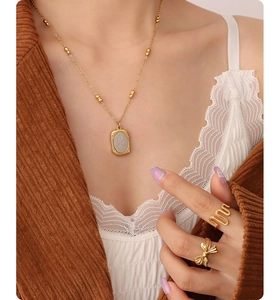 Detail of 18K gold-plated rose flower pendant and pearl bead chain on model